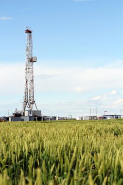oil drilling rig on green wheat field clipart