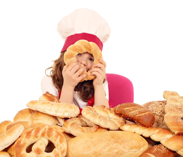 Klein meisje kok met brood broodjes en pretzels — Stockfoto