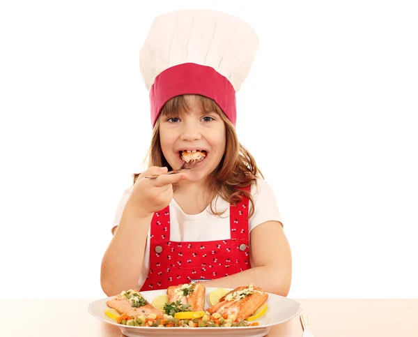 Hungry little girl cook eat salmon seafood — Stock Photo, Image