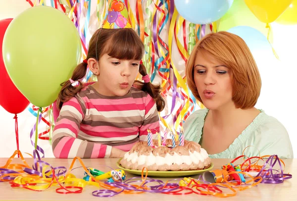 Mom and daughter blowing birthday candles — Stock Photo, Image