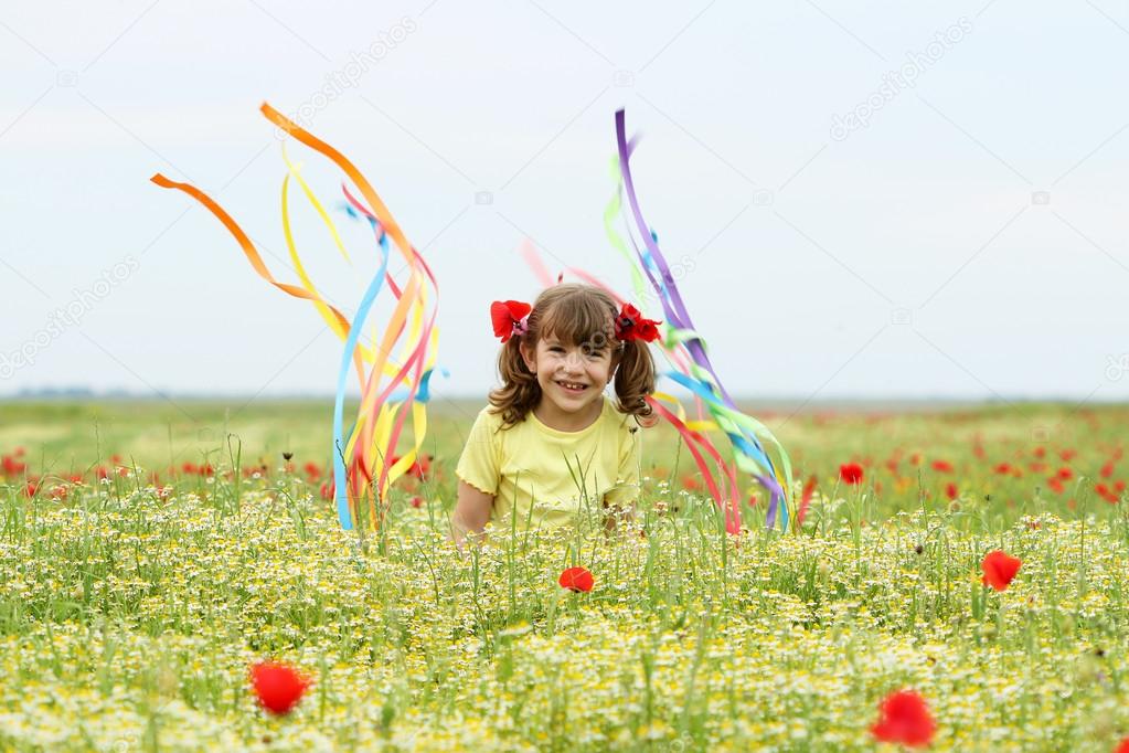 happy little girl waving with colorful ribbons on wildflower mea