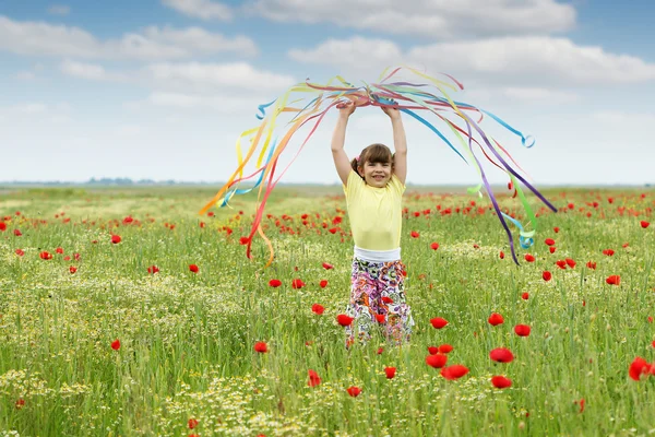 Vacker liten flicka vifta med färgglada band på äng — Stockfoto