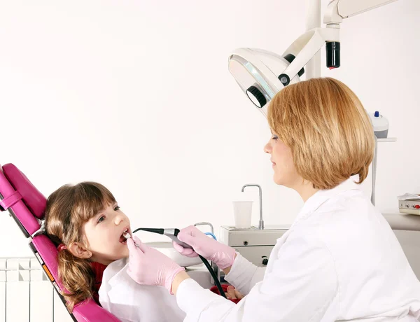 Dentista mujer y niña pequeña paciente en el consultorio dental —  Fotos de Stock