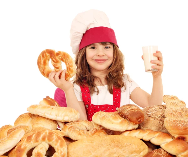 Menina feliz cozinhar com pretzel e copo de leite — Fotografia de Stock