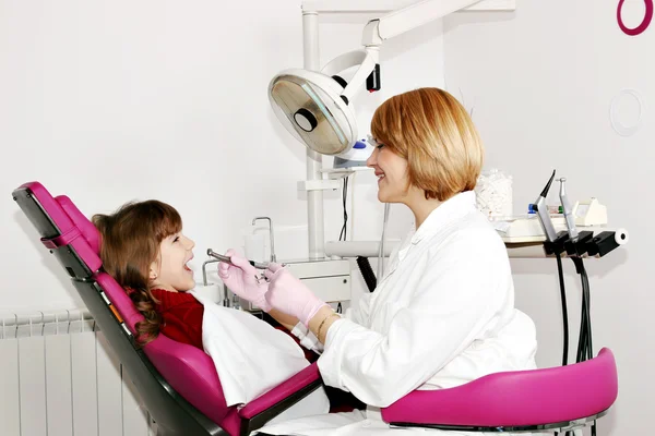 Dentista mujer y niña pequeña paciente en el consultorio dental — Foto de Stock