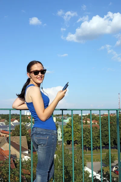 Šťastný dospívající dívka poslech hudby na smartphonu — Stock fotografie