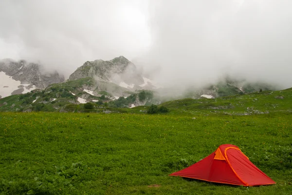 Червоний туристичний намет проти гір, вкритих хмарами — стокове фото
