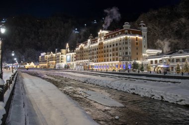 Sochi, Krasnaya Polyana, Rusya - 20 Ocak 2022: Rosa Khutor kayak merkezindeki otel ve dükkanlar. Mzymta Nehri 'nin seti..