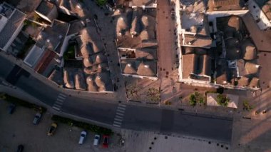 İtalya 'daki Alberobello kasabasının hava manzarası. İnsansız hava aracı güneş doğarken eski kasaba binalarının üzerinde uçuyor.