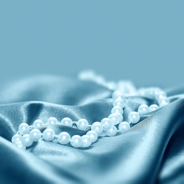 Perlas sobre un fondo de tela de seda — Foto de Stock