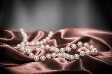 Pearls on a silk fabric background clipart