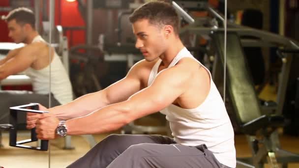 Hombre deportivo guapo está haciendo ejercicio en el centro de gimnasia — Vídeos de Stock