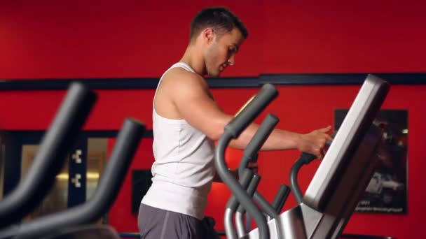 Bonito homem desportivo está se exercitando no centro de fitness — Vídeo de Stock