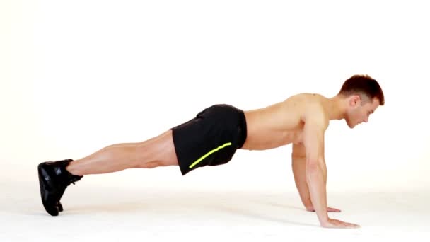 Hombre musculoso guapo haciendo ejercicio sobre fondo blanco — Vídeo de stock