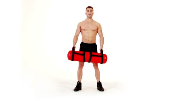 Handsome muscular man exercising with water bag on white — Stock Video