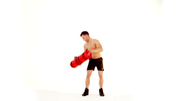 Schöner muskulöser Mann, der mit Wassersack auf weißem Grund trainiert — Stockvideo