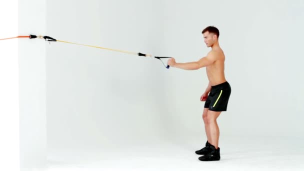 Przystojny mężczyzna mięśni, ćwiczenia z gumy na biały — Wideo stockowe