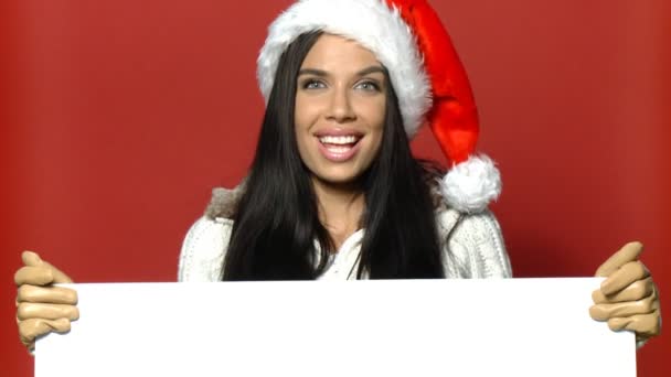 Девушка в шляпе Санта Клауса держит пустую доску — стоковое видео