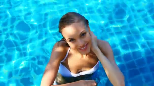 Όμορφη νεαρή γυναίκα που αναπαύεται στην πισίνα, την ηλιόλουστη ημέρα — Αρχείο Βίντεο
