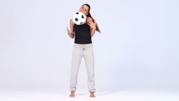 Hermosa mujer con pelota de fútbol sobre fondo blanco — Vídeos de Stock