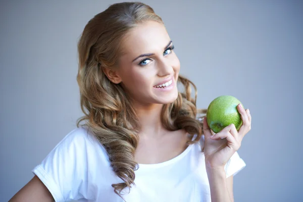 Foto de la cabeza de la mujer sosteniendo manzana verde contra gris —  Fotos de Stock