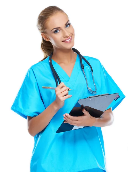 Söt sköterska tittar på kameran och leende med writingpad — Stockfoto