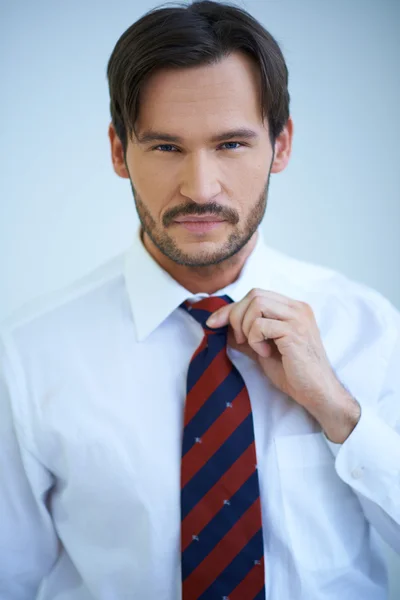 Attractive man adjusting his tie — Stock Photo, Image