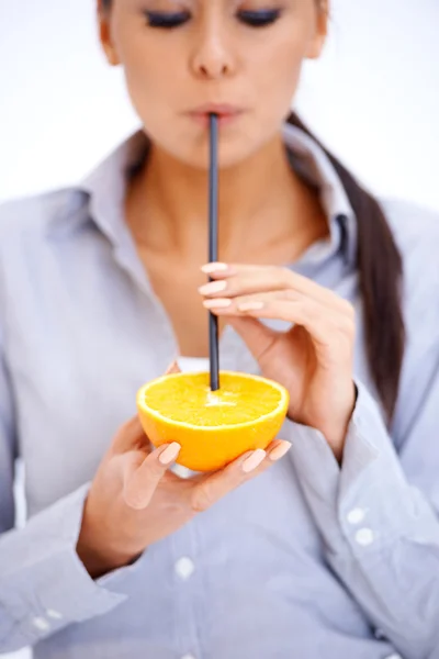 Woman drinks orange juice through a straw — Stock Photo, Image