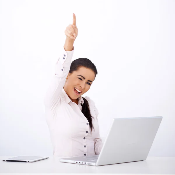 Mujer feliz sentada en su escritorio, con un brazo levantado — Foto de Stock