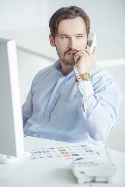 Hombre de negocios ocupado hablando por teléfono en su escritorio — Foto de Stock