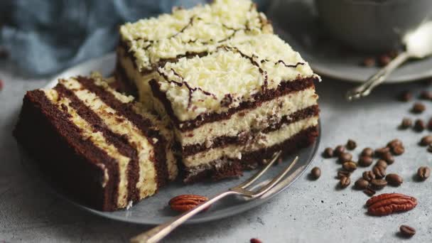 Hausgemachter, mit weißer Schokolade bestreuter Schichtkuchen. Serviert mit einer Tasse Kaffee auf einem grauen Beton — Stockvideo