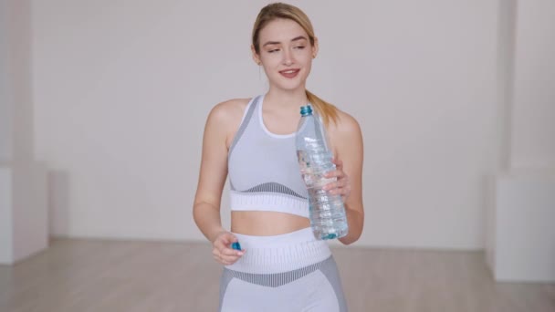 Щаслива жінка спортсменка п'є воду — стокове відео