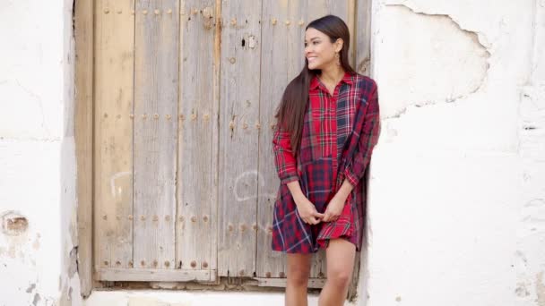 Giovane donna in abito alla moda in piedi vicino muro d'epoca e guardando la fotocamera — Video Stock