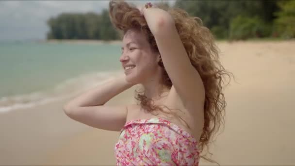 自信のある女性です髪を振って砂浜を歩くとカメラを見て — ストック動画