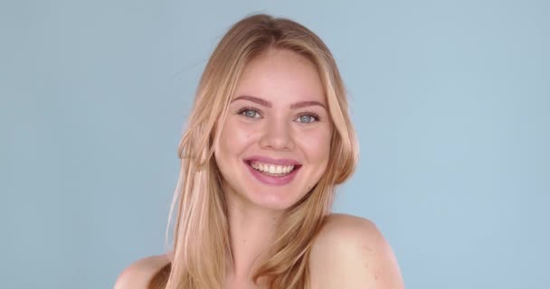 Портрет красивої блондинки з довгим волоссям, позує в студії на синьому фоні — стокове відео