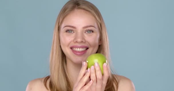 Close up studio shot of smiling young woman holding green apple — Vídeo de Stock