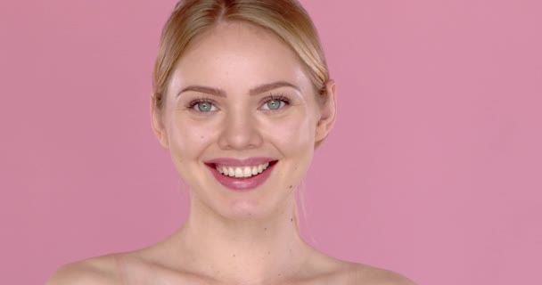 Syuting video gerak lambat gadis cantik tersenyum, terisolasi di latar belakang merah muda. Bahu telanjang — Stok Video