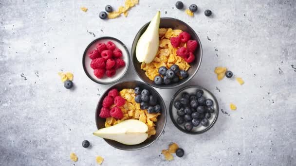 Copos de maíz dorados con frutas frescas de frambuesas, arándanos y pera en tazón de cerámica — Vídeos de Stock