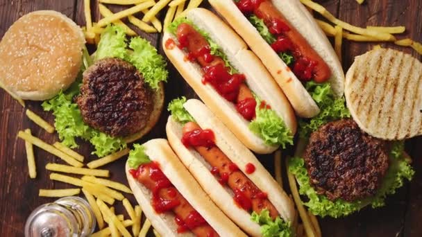 Gyorséttermi választék. Rozsdás fa asztalra helyezett hamburger és hot dog — Stock videók