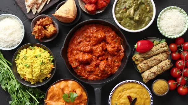 Różne indyjskie potrawy na stole. Pikantny kurczak Tikka Masala w żelaznej patelni — Wideo stockowe