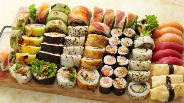 Bovenaanzicht van diverse sushi en rollen geplaatst op houten plank. Japans voedselfeest — Stockvideo