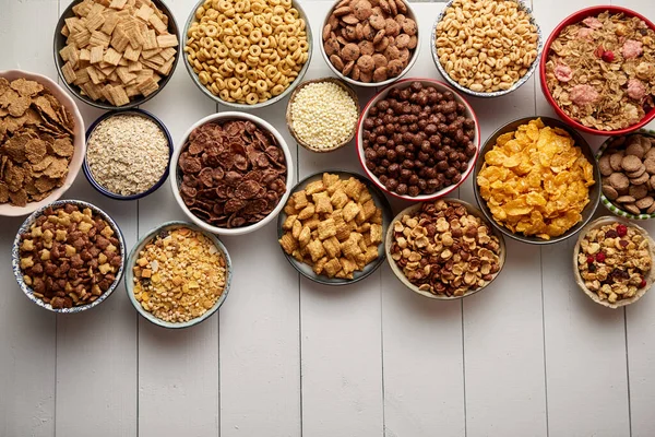 Surtido de diferentes tipos de cereales colocados en cuencos de cerámica en la mesa —  Fotos de Stock