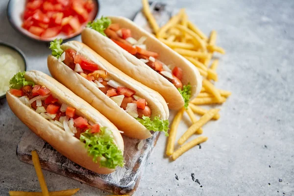 Assortiment van drie lekkere hotdogs, geplaatst op houten snijplank — Stockfoto