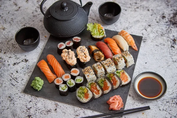 Ποικιλία από διαφορετικά είδη sushi ρολά τοποθετημένα στο μαύρο του σκάφους πέτρα — Φωτογραφία Αρχείου