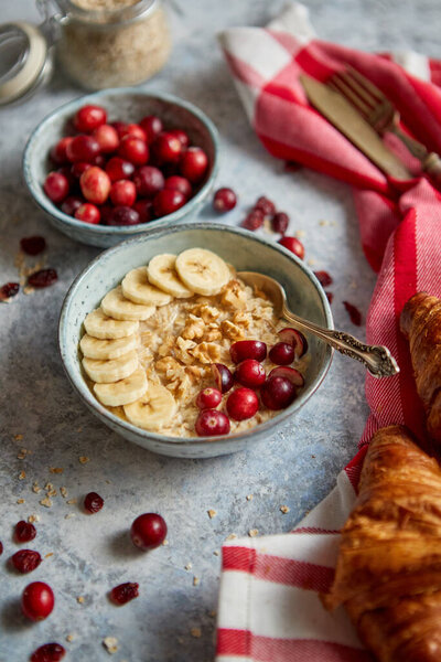 Ceramic bowl of oatmeal porridge with banana, fresh cranberries and walnuts Stock Image
