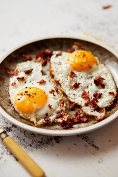 Two fresh fried eggs with crunchy crisp bacon served on rustic plate Royalty Free Stock Photos