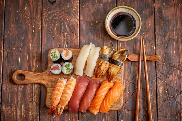 Set de Sushi. Diferentes tipos de rollos de sushi en tablero de servir de madera — Foto de Stock