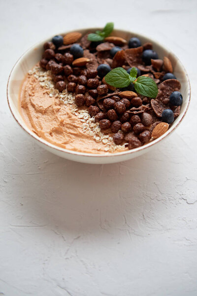 Chocolate and blueberry smoothie or yogurt. With cocoa cornflakes, granola, mint leaves and almonds Stock Photo