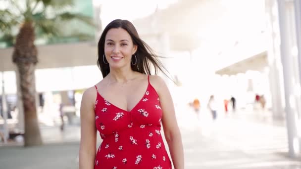 Glimlachende vrouw in trendy jurk lopen op straat en kijken naar de camera — Stockvideo