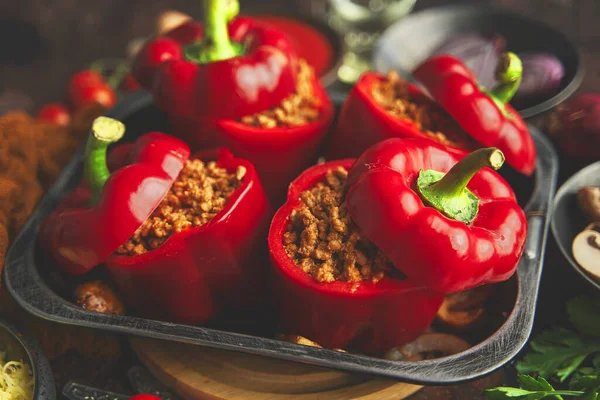 Peperoni di paprika ripieni rossi in pentola di ferro con vari ingredienti sul lato — Foto Stock